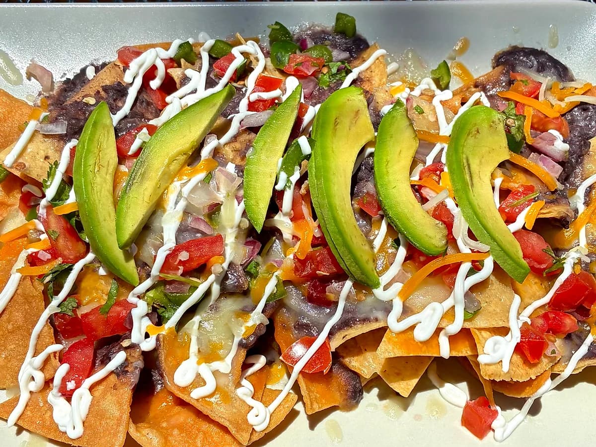 The $10 World Cup nacho plate, fanned avocado over black beans, pico de gallo, and crema